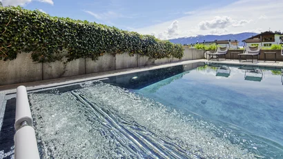 Moderner Außenpool mit Whirlbereich und Blick auf Berge und Himmel