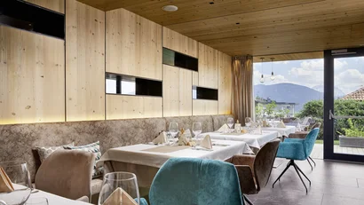 Modernes Restaurant mit Holzwand und Blick auf Berge durch Fenstertür