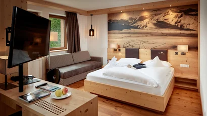 Modernes Hotelzimmer mit Holzmöbeln und Bergfoto über dem Bett