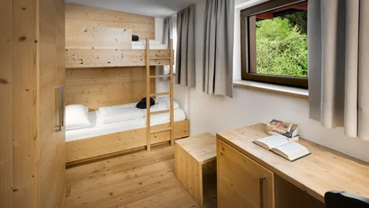 Kleines Schlafzimmer mit Etagenbett, Holzmöbeln und Fenster mit Blick ins Grüne