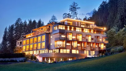 Modernes beleuchtetes Hotelgebäude im Wald bei Abenddämmerung