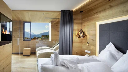 Modernes Hotelzimmer mit Holzverkleidung, gemütlichem Bett und Bergblick