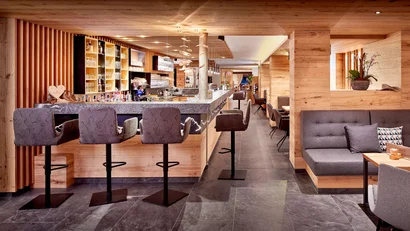 Moderner Holzbarbereich mit grauen Barhockern und gemütlichen Sitzplätzen