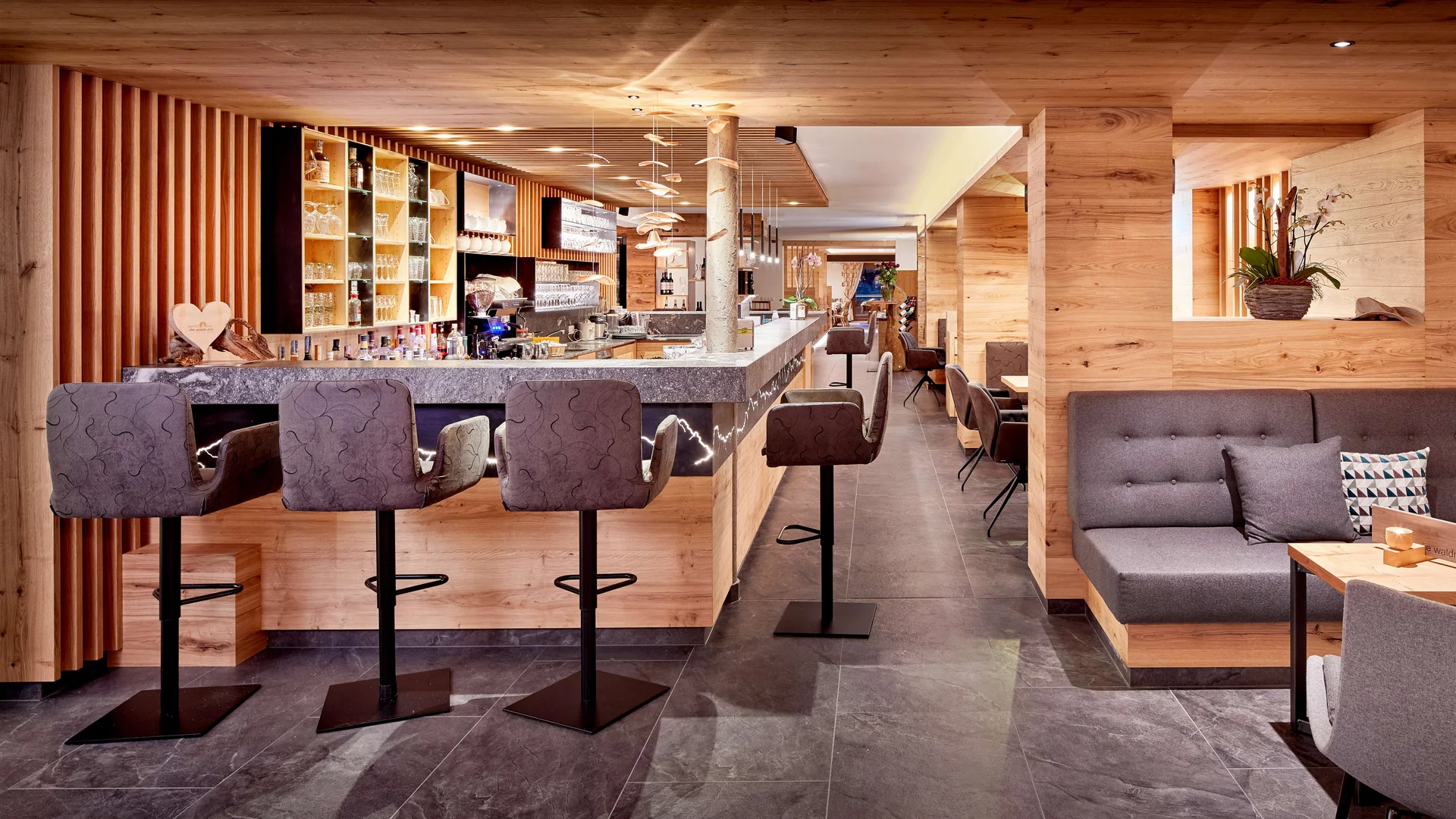 Moderner Holzbarbereich mit grauen Barhockern und gemütlichen Sitzplätzen