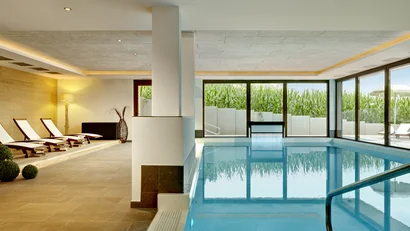 Moderner Innenpool mit Liegestühlen und großen Fenstern zur Außenansicht