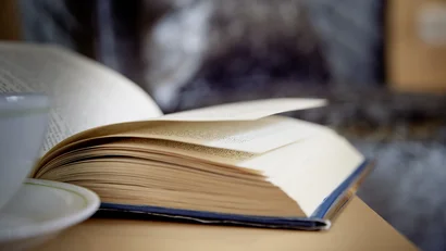 Aufgeschlagenes Buch auf einem Holztisch mit unscharfem Hintergrund