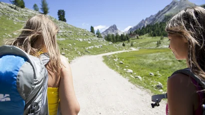 Zwei Frauen wandern auf einem Bergweg bei sonnigem Wetter