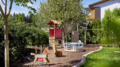 Kinderspielplatz mit Schaukel, Karussell und Kletterturm im Garten